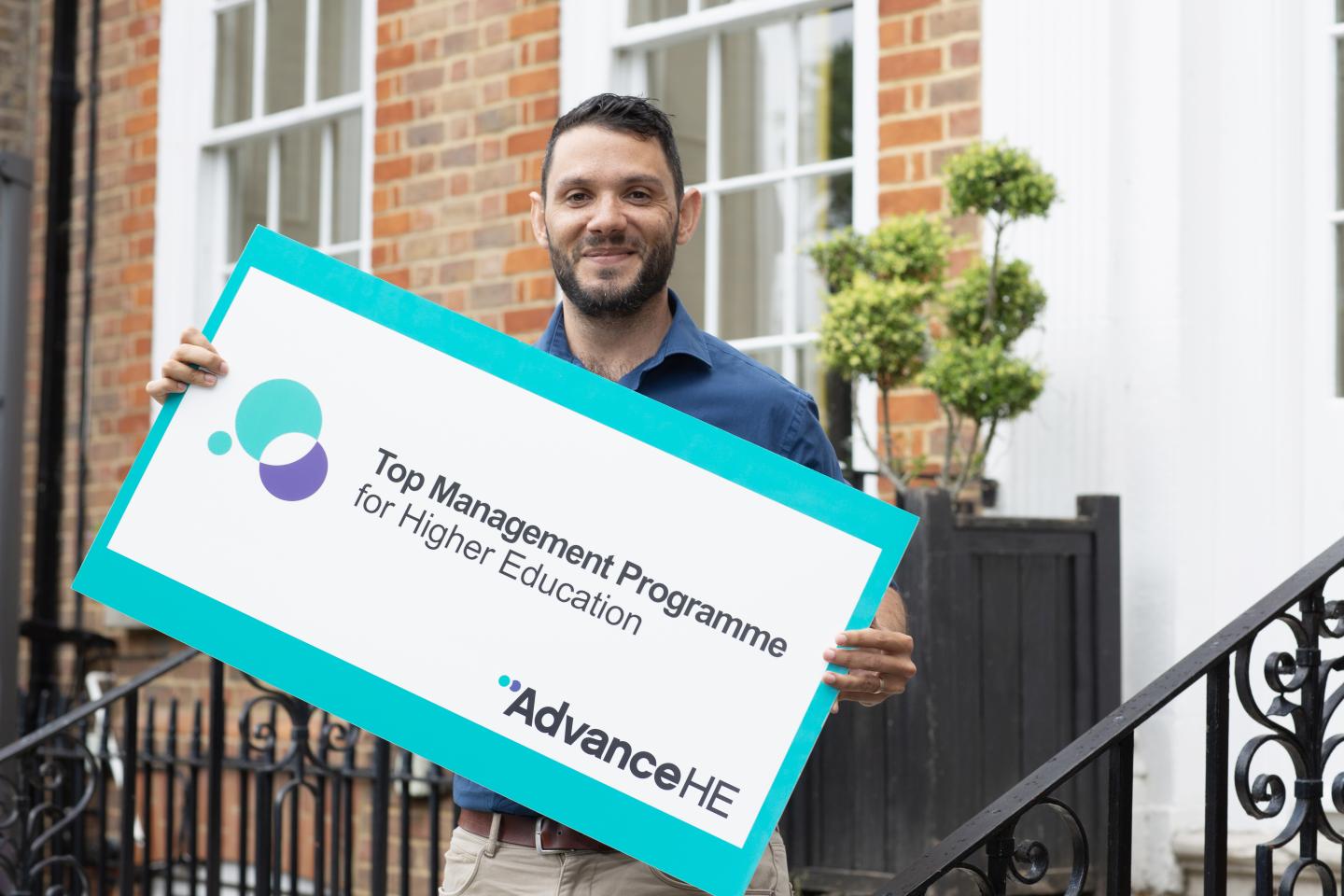 Man holding a banner saying 'Top Management Programme' Advance HE