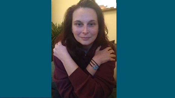 Image of Dr Despina Moschou, Senior Lecturer at the University of Bath, doing the #EmbraceEquity pose of hugging oneself with arms crossed and hands resting on shoulders in a 