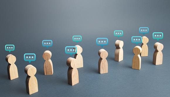 Abstract image of wooden people figures with comment clouds above their heads to represent giving feedback.