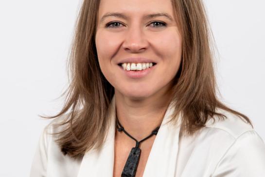 Professor Emily Nordmann wearing a white blazer and light-coloured top, shown in a professional head‑and‑shoulders portrait against a plain background.