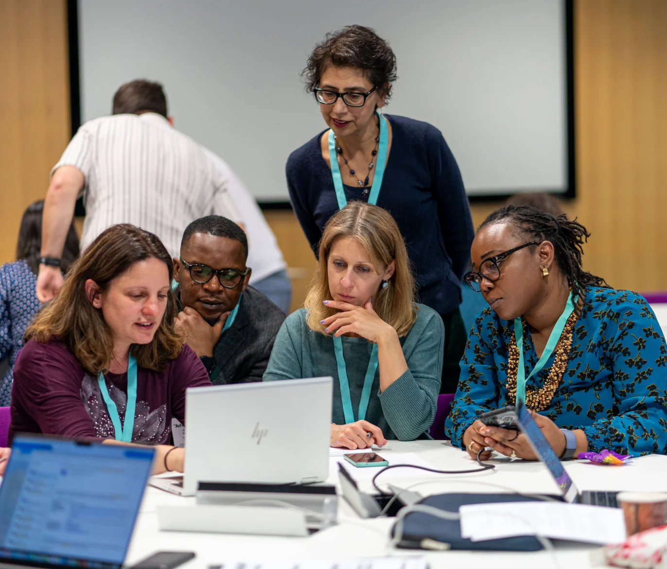 Group of five people looking at a laptop