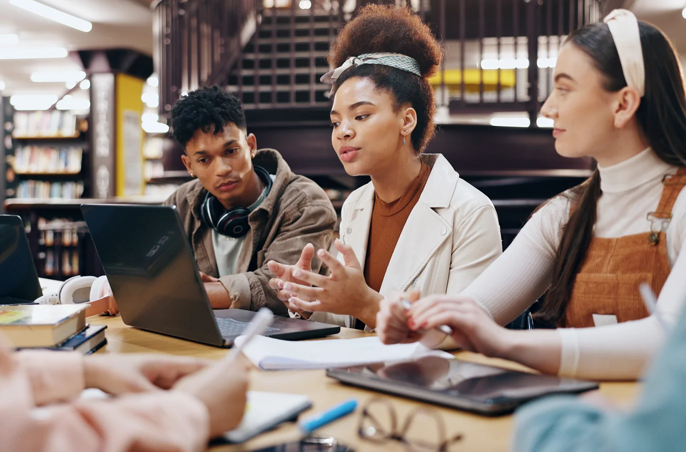A group of students gathered around a laptop while one of them explains something to the others,