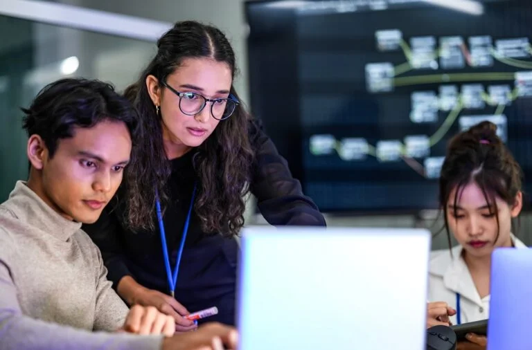 Three students working around laptops