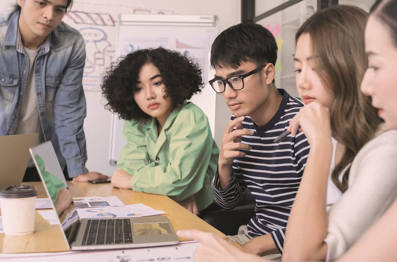 A group of students gathered around a laptop and various notes.